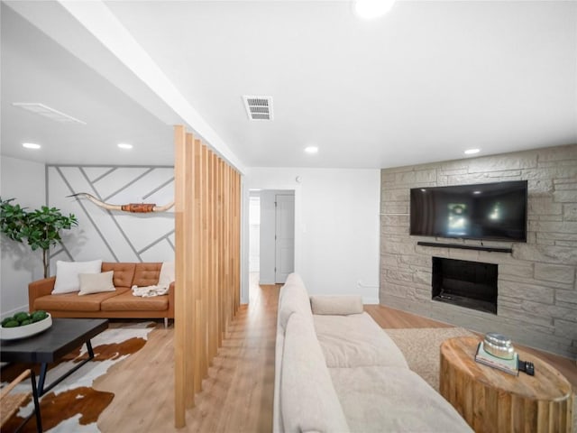 living room featuring a stone fireplace and light wood-type flooring