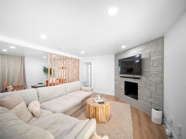 living room with light wood-type flooring and a stone fireplace