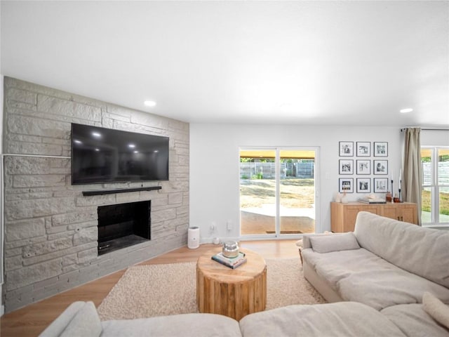 living room with a stone fireplace and light wood-type flooring