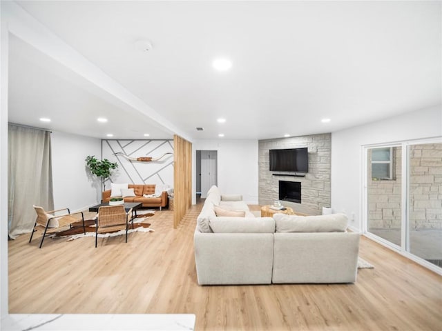 living room featuring a stone fireplace and light wood-type flooring