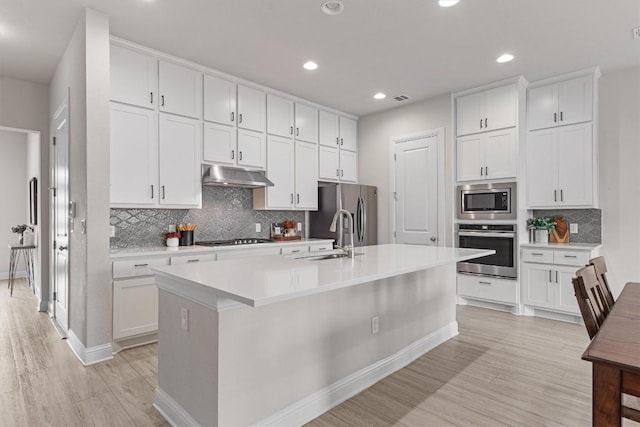 kitchen with sink, light hardwood / wood-style flooring, a kitchen island with sink, stainless steel appliances, and white cabinets