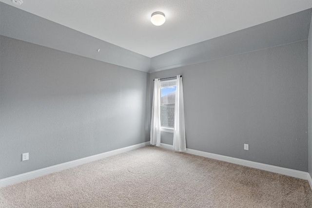 carpeted empty room with vaulted ceiling