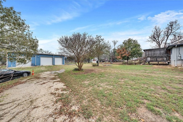 view of yard with a garage, an outbuilding, and a wooden deck