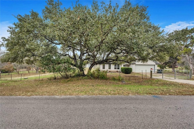 view of property hidden behind natural elements with a rural view and a garage