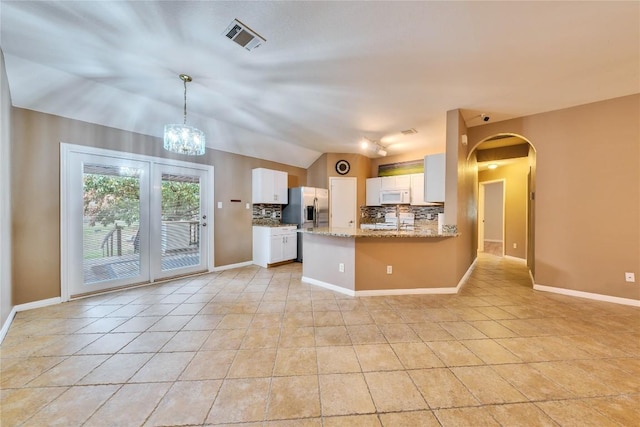 kitchen with white cabinetry, light stone counters, backsplash, kitchen peninsula, and lofted ceiling