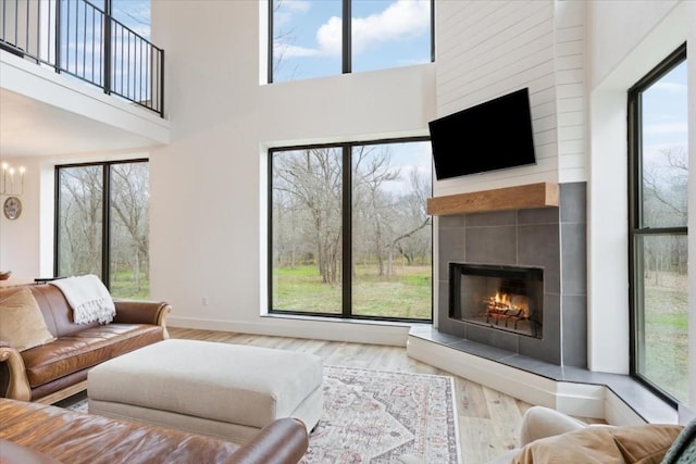 living room featuring a fireplace, a towering ceiling, an inviting chandelier, and light hardwood / wood-style flooring