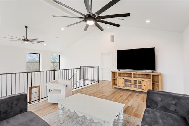 living room featuring ceiling fan, light wood-type flooring, and vaulted ceiling