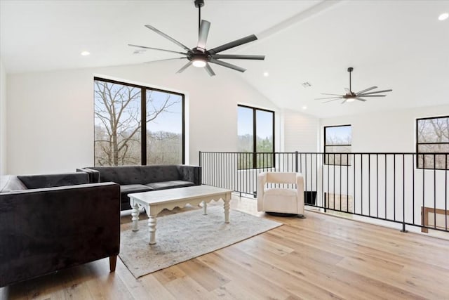 living room with ceiling fan, light hardwood / wood-style floors, and vaulted ceiling