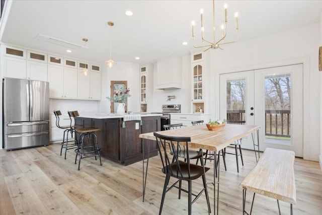 dining area featuring french doors, light wood-type flooring, and an inviting chandelier