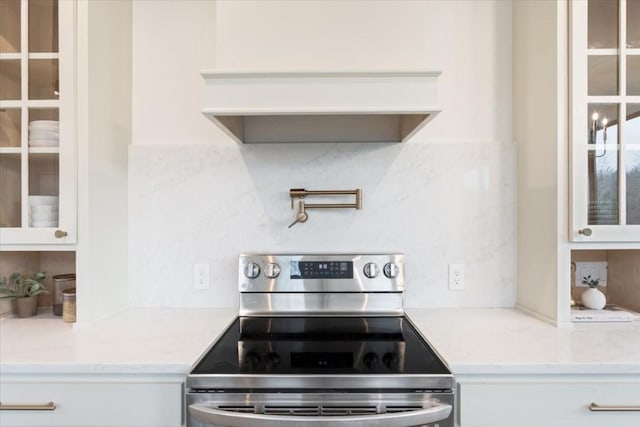 kitchen with white cabinetry, light stone counters, tasteful backsplash, and stainless steel electric range