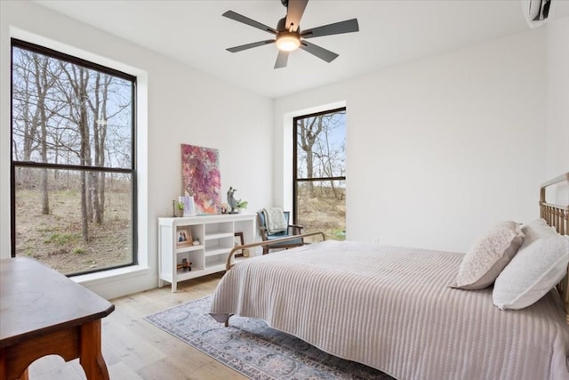 bedroom with multiple windows, light wood-type flooring, and ceiling fan