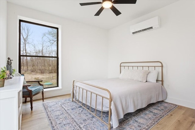 bedroom with ceiling fan, light hardwood / wood-style floors, and an AC wall unit