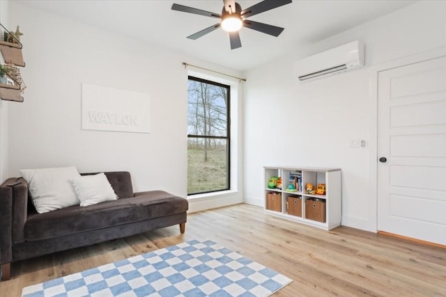 living area featuring ceiling fan, light hardwood / wood-style floors, a wealth of natural light, and a wall mounted AC