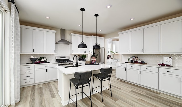 kitchen with white cabinetry, stainless steel appliances, wall chimney range hood, pendant lighting, and decorative backsplash