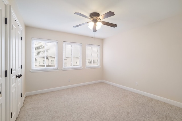 spare room with a wealth of natural light, ceiling fan, and light carpet