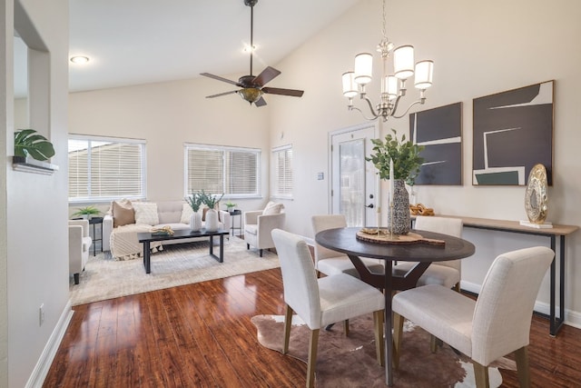 dining area with hardwood / wood-style floors, ceiling fan with notable chandelier, and high vaulted ceiling