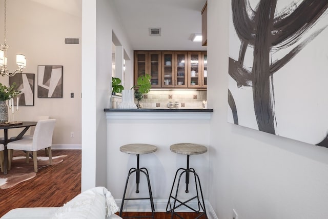 bar featuring decorative backsplash, pendant lighting, and dark hardwood / wood-style floors