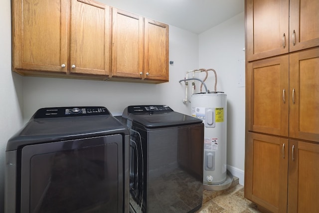 washroom with cabinets, washing machine and dryer, and water heater