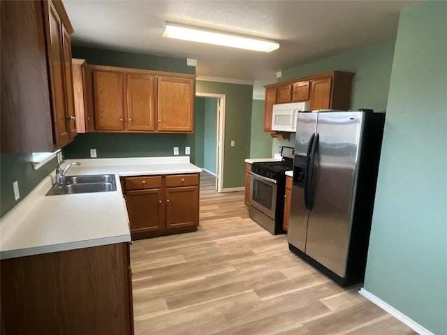 kitchen with sink, stainless steel appliances, and light wood-type flooring