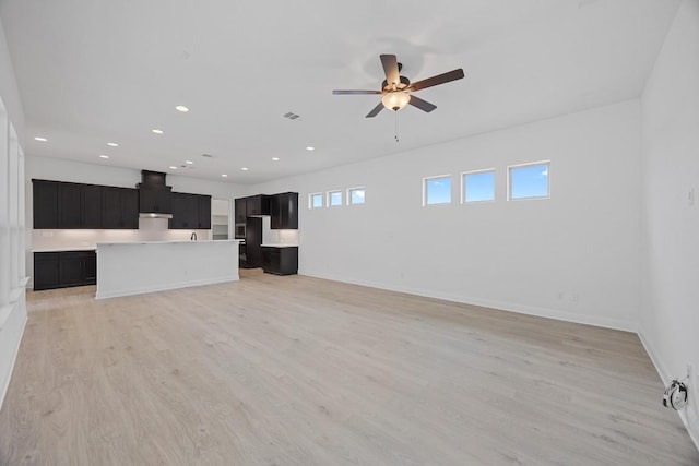 unfurnished living room with a wealth of natural light, ceiling fan, and light wood-type flooring