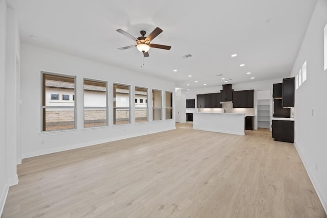 unfurnished living room featuring ceiling fan and light wood-type flooring