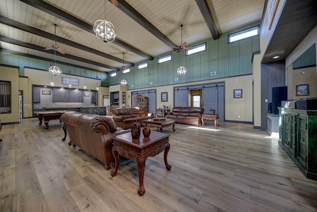 living room with beamed ceiling, a high ceiling, and light wood-type flooring