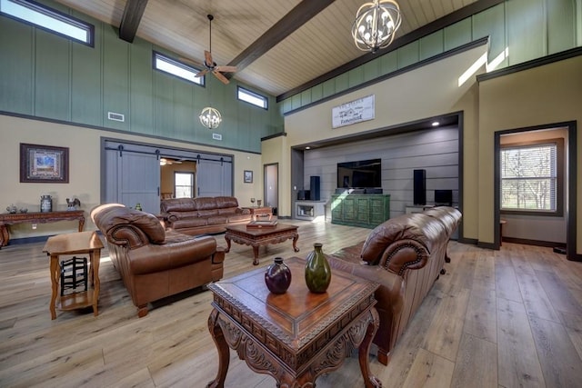 living room featuring beam ceiling, a barn door, wooden ceiling, a high ceiling, and light hardwood / wood-style floors