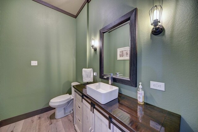 bathroom featuring hardwood / wood-style floors, vanity, lofted ceiling, toilet, and ornamental molding