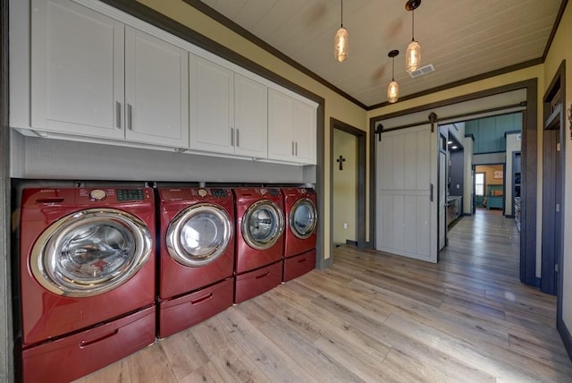 laundry area with cabinets, crown molding, a barn door, washing machine and dryer, and light hardwood / wood-style floors