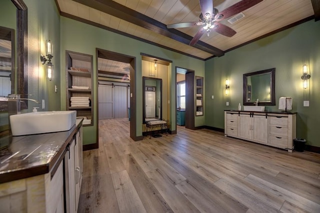 interior space featuring a barn door, sink, beamed ceiling, and light wood-type flooring