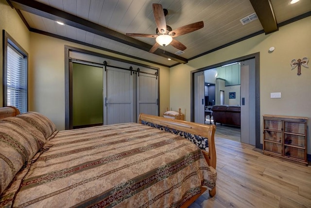 bedroom featuring beam ceiling, ceiling fan, a barn door, light hardwood / wood-style flooring, and wood ceiling