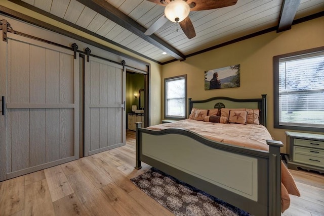 bedroom featuring beamed ceiling, ceiling fan, a barn door, and light hardwood / wood-style floors