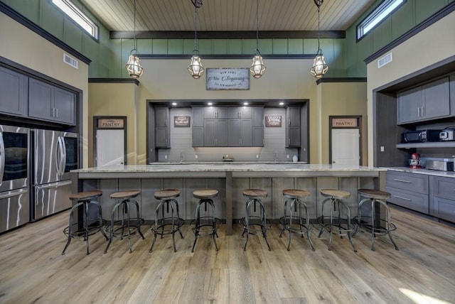 kitchen featuring decorative backsplash, a high ceiling, stainless steel fridge, and gray cabinetry