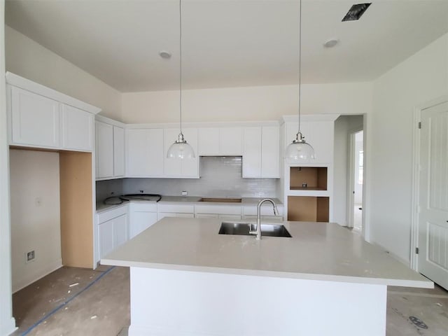 kitchen with white cabinets, sink, decorative light fixtures, and an island with sink