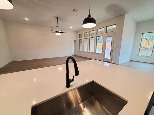 kitchen with wood finished floors, a sink, visible vents, open floor plan, and hanging light fixtures