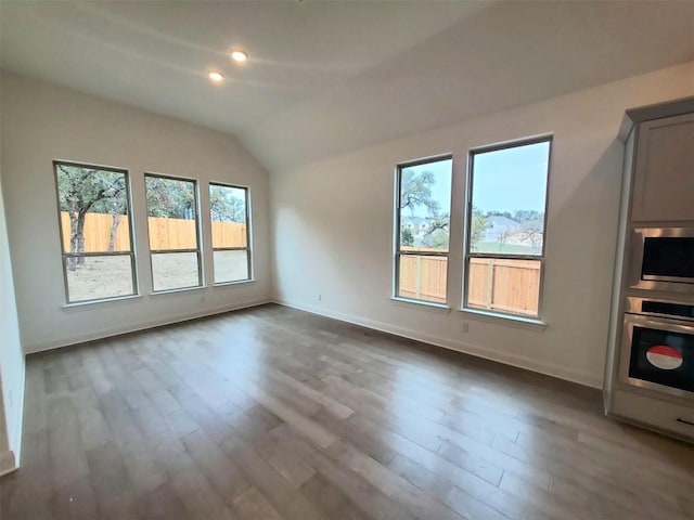 unfurnished living room featuring dark wood-style floors, vaulted ceiling, and baseboards