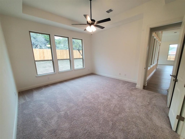empty room featuring a ceiling fan, visible vents, carpet, and baseboards