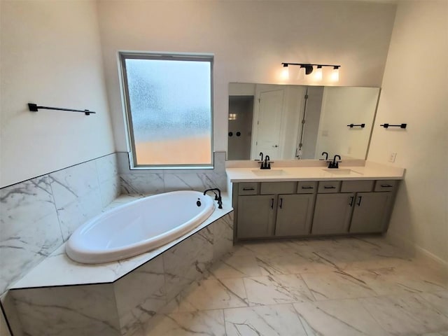 full bath with marble finish floor, a garden tub, double vanity, and a sink
