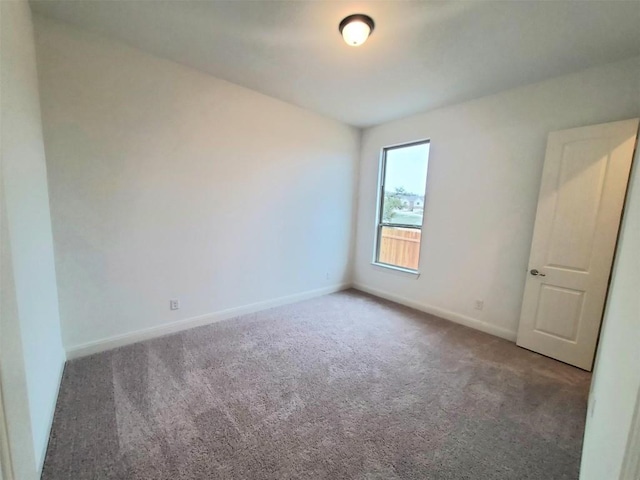 spare room featuring carpet floors and baseboards