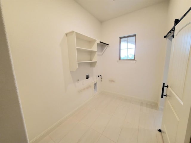 laundry room featuring a barn door, gas dryer hookup, electric dryer hookup, laundry area, and baseboards