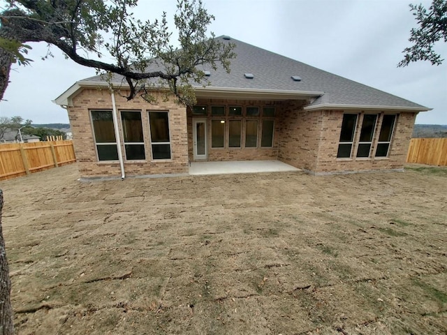 rear view of property featuring fence private yard, brick siding, and a patio