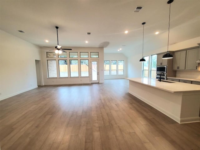 interior space featuring stainless steel microwave, a sink, visible vents, light countertops, and wood finished floors