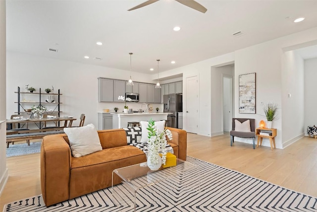 living room with ceiling fan, sink, and light hardwood / wood-style flooring