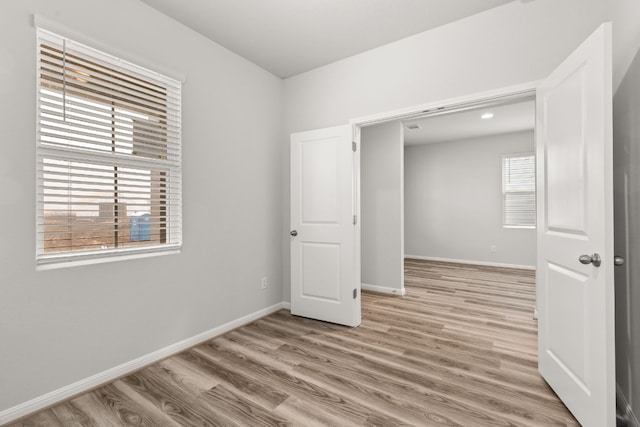 unfurnished bedroom featuring multiple windows and light wood-type flooring