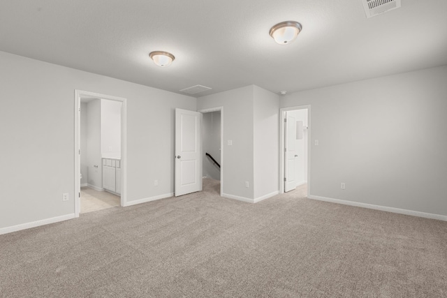 unfurnished bedroom featuring ensuite bath and light colored carpet