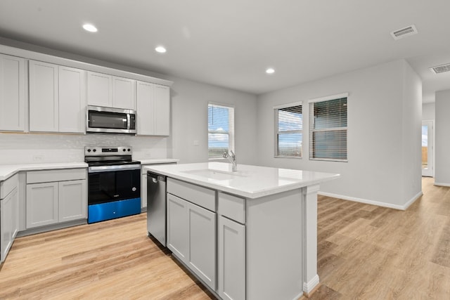 kitchen with light hardwood / wood-style floors, sink, stainless steel appliances, and a center island