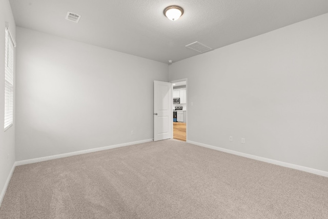 spare room with light carpet and a textured ceiling