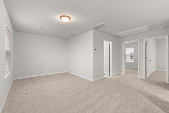 unfurnished room with light colored carpet and a textured ceiling