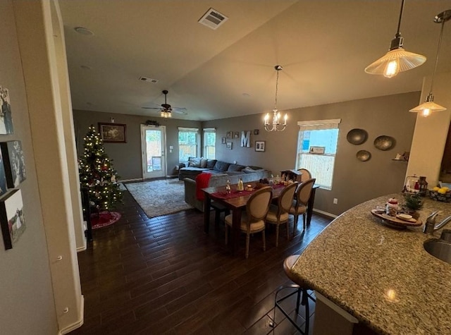 dining area with ceiling fan with notable chandelier, dark hardwood / wood-style flooring, lofted ceiling, and sink