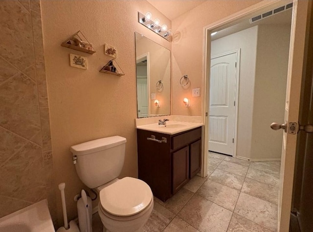 bathroom with a washtub, vanity, and toilet